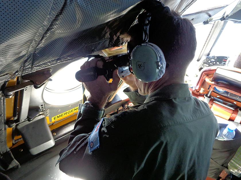 A Royal Australian Air Force pilot of an AP-3C Orion maritime patrol aircraft scans the surface of the sea near the west of Peninsula Malaysia in this handout picture by the Royal Australian Air Force, released via the Australian government's Department o