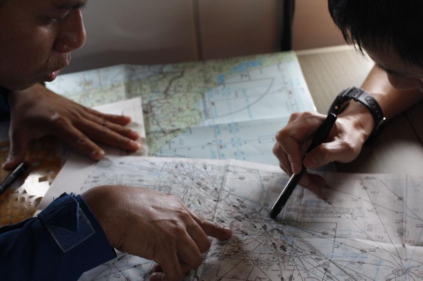 A Japan Coast Guard (JCG) studies a map with a Malaysian Maritime Enforcement Agency pilot (left) in JCG's Gulfstream V Jet aircraft over the waters of the South China Sea March 15, 2014. u00e2u20acu201d Reuters pic