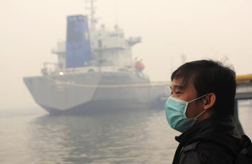 A passenger wearing a mask stands in thick haze as he waits for his ferry heading to Malaysia, in Dumai port, in Indonesia Riau province March 13, 2014. u00e2u20acu201d Reuters pic