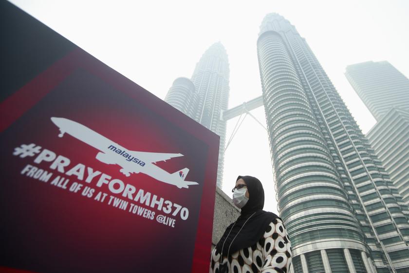 A woman wearing a mask against the haze walks past a board saying 'Pray for MH370' in front of the Kuala Lumpur City Centre, March 14, 2014.u00c2u00a0u00e2u20acu201d Reuters pic
