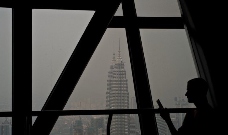 Malaysiau00e2u20acu2122s landmark Petronas Twin Towers are seen covered in haze as a tourist sits on the KL Tower observation deck in Kuala Lumpur on March 5, 2014. u00e2u20acu201d AFP pic