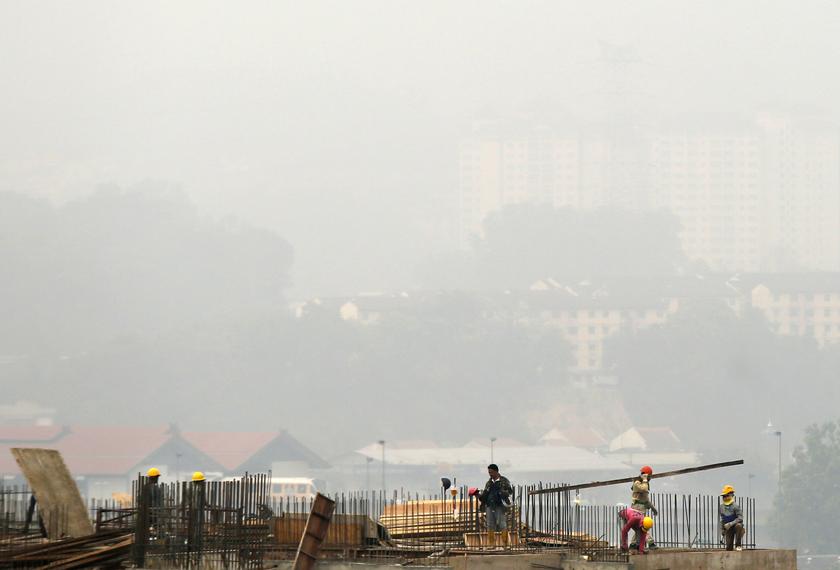 Construction workers erect a new office tower in front of a Kuala Lumpur skyline blanketed by haze March 3, 2014. u00e2u20acu201d Reuters pic