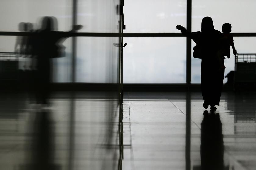 A woman carries her child through the departure hall of the Kuala Lumpur International Airport March 11, 2014.u00c2u00a0u00e2u20acu201d Reuters pic