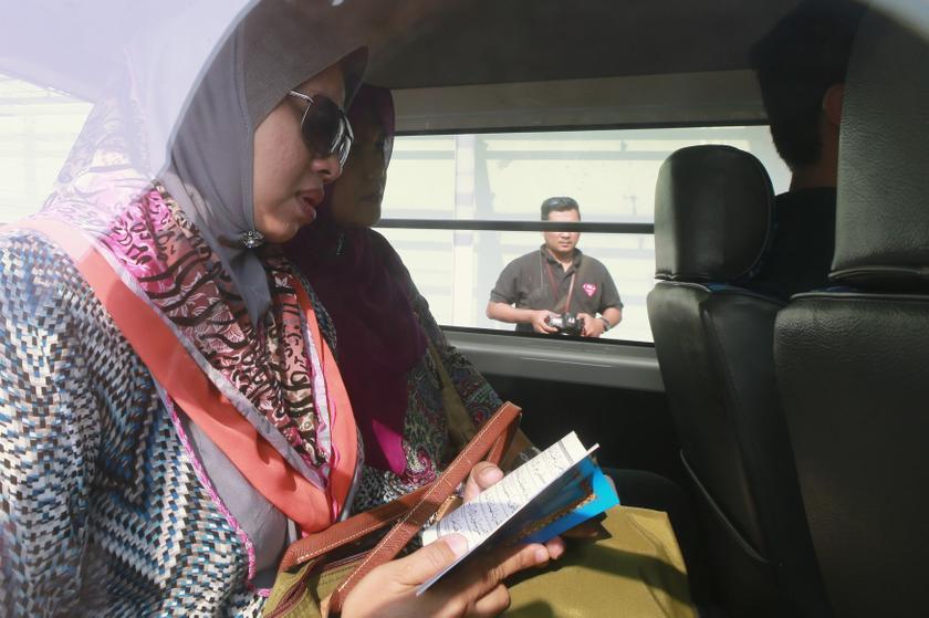 Family members of those onboard the missing Malaysia Airlines flight read the Quran inside a car outside the hotel where they are staying in Putrajaya March 9, 2014. u00e2u20acu201d Reuters pic
