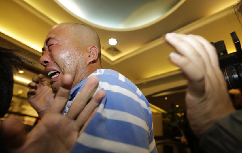A family member of a passenger aboard MAS flight MH370 cries after watching a television broadcast of a news conference, in the Lido hotel in Beijing, March 24, 2014.
