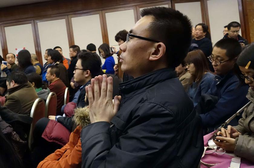 A relative of a passenger of Malaysia Airlines flight MH370 puts his palms together as he prays for his family member at the Lido Hotel in Beijing, March 10, 2014.