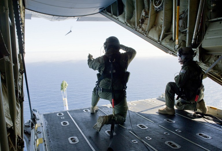A photo taken on March 20, 2014, shows Royal Australian Air Force Loadmasters, Sergeant Adam Roberts (L) and Flight Sergeant John Mancey (R), preparing to launch a Self Locating Data Marker Buoy from a C-130J Hercules aircraft in the southern Indian Ocean