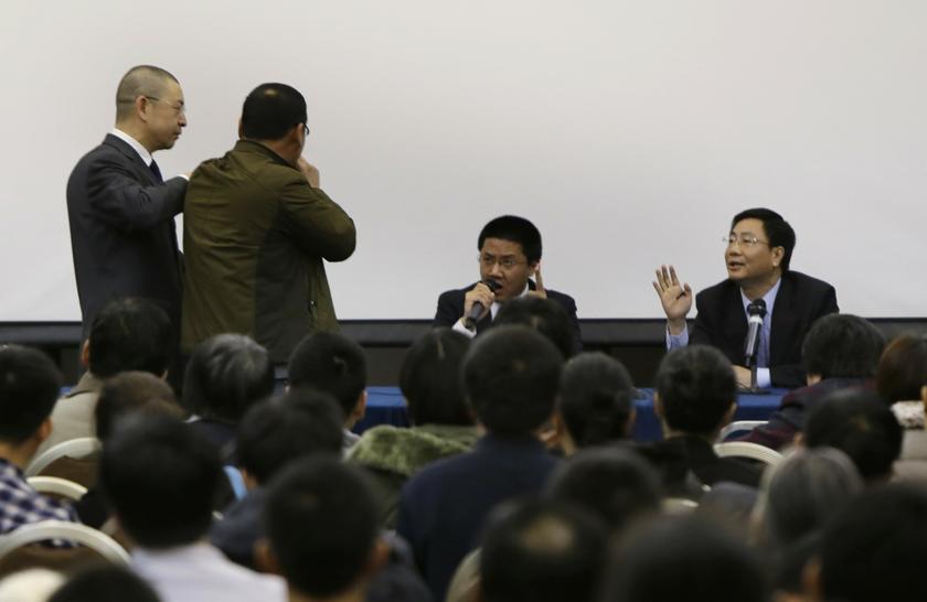 A hotel security personnel tries to keep the distance between a relative of a passenger aboard Malaysia Airlines flight MH370 from Malaysia Airlines representatives as the relative asks questions during a meeting at Lido Hotel in Beijing, March 16, 2014. 