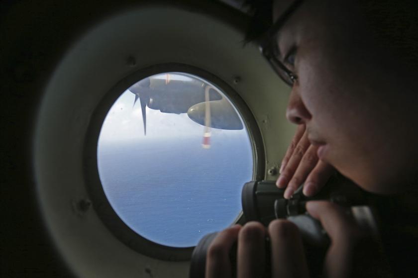 A member of the military personnel looks out of a Republic of Singapore Air Force (RSAF) C130 transport plane during a search for the missing Malaysia Airlines MH370 plane over the South China Sea March 11, 2014. u00e2u20acu201d Reuters pic