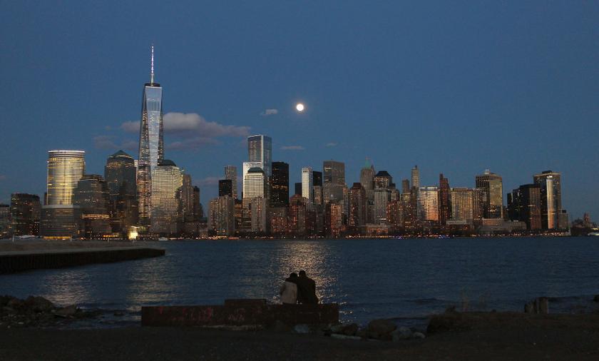 The moon rises behind the skyline of New York's Lower Manhattan as two people watch from a park along the Hudson River in Jersey City, New Jersey, March 15, 2014. u00e2u20acu201d Reuters pic