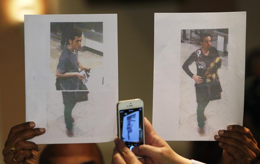 A policeman holds up photos of the two men whom they believe were travelling onboard the missing Malaysia Airlines MH370 on stolen passports after a news conference in KLIA on March 11, 2014. — Reuters pic