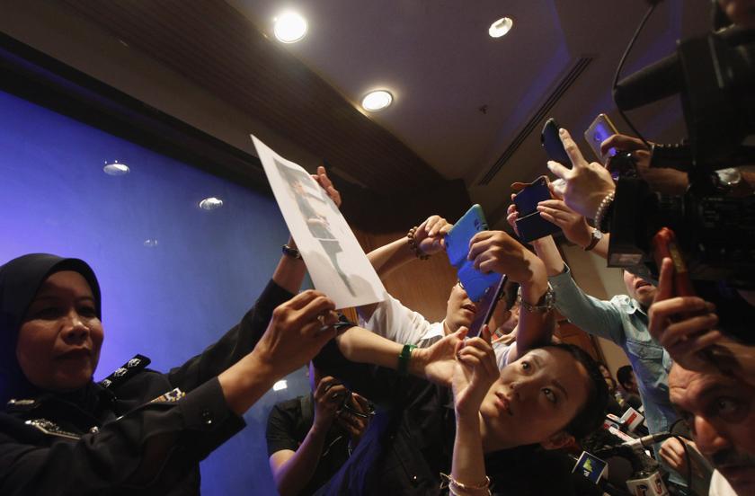 A policewoman holds up a photo of one of the two men whom they believe were travelling on board the missing Malaysia Airlines MH370 on stolen passports after a news conference in Kuala Lumpur International Airport March 11, 2014. u00e2u20acu201d Reuters pic