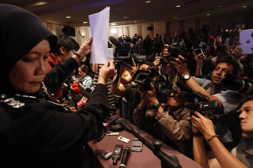 A policewoman holds up a photo of one of the two men whom they believe were travelling on board the missing Malaysia Airlines MH370 on stolen passports after a news conference in Kuala Lumpur International Airport March 11, 2014. u00e2u20acu201d Reuters pic