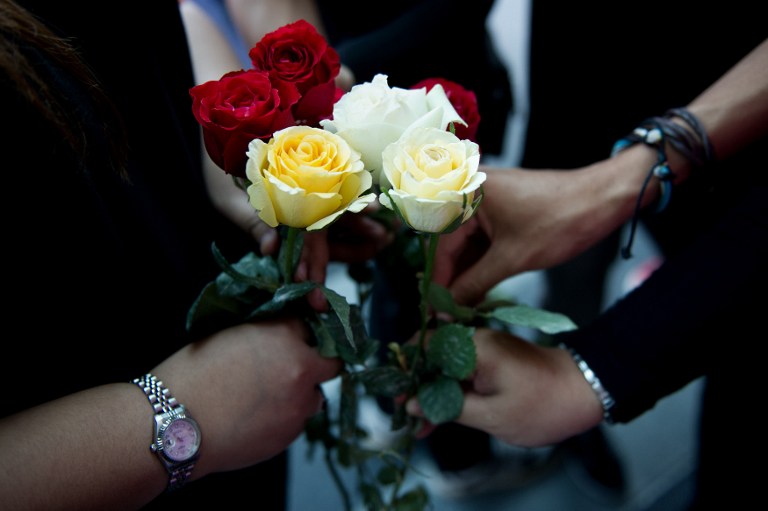 Members of a youth group hold roses as they pray for the missing Malaysia Airlines Boeing 777-200 plane at a hotel in Putrajaya on March 10, 2014. u00e2u20acu201d AFP pic