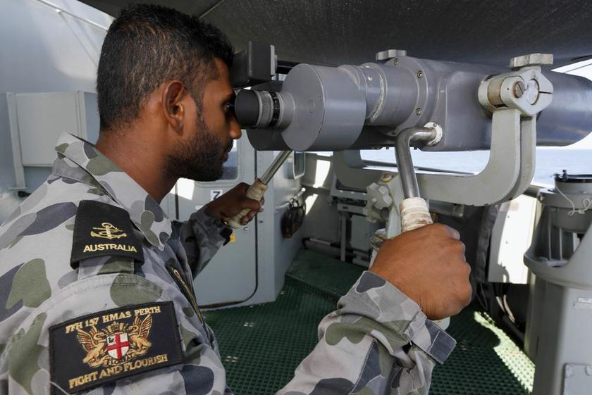 Leading Seaman Boatswain's Mate Graham Pereira looks through the telescopic binoculars on the starboard bridge wing aboard the Australian Navy ship HMAS Perth in the southern Indian Ocean, during the search for the missing Malaysian Airlines flight MH370 