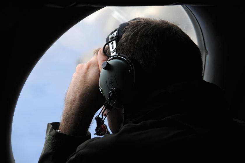 A crew member aboard a Royal New Zealand Air Force P-3K2 Orion aircraft looks out an observation window as they fly over the southern Indian Ocean to continue the search for flight MH370 April 13, 2014. Reuters pic
