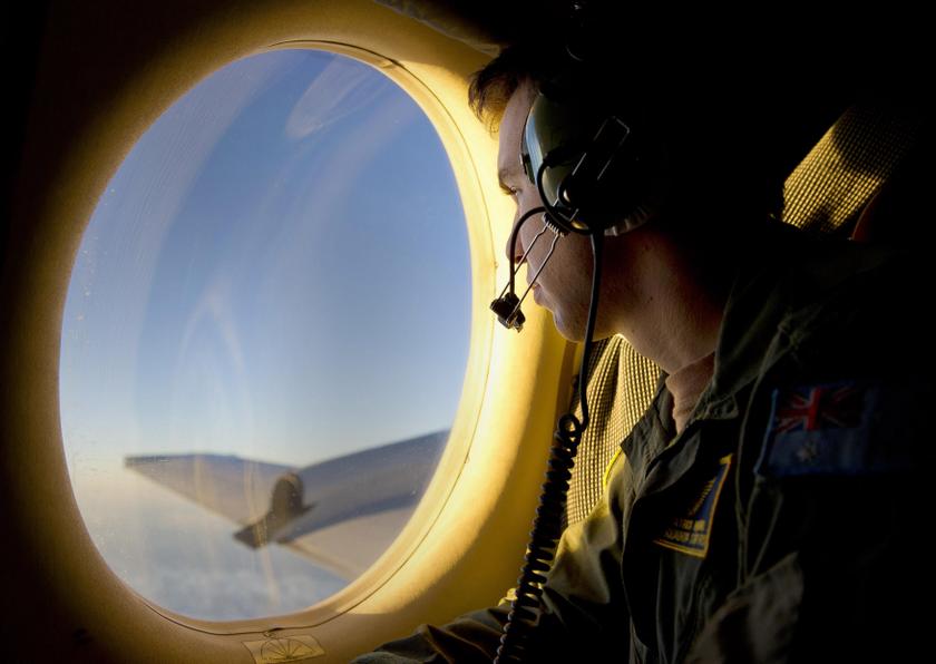 Royal Australian Air Force (RAAF) Airborne Electronics Analyst Sergeant Patrick Manser looks out of an observation window aboard a RAAF AP-3C Orion aircraft during the search in the southern Indian Ocean for debris from the missing Malaysian Airlines flig