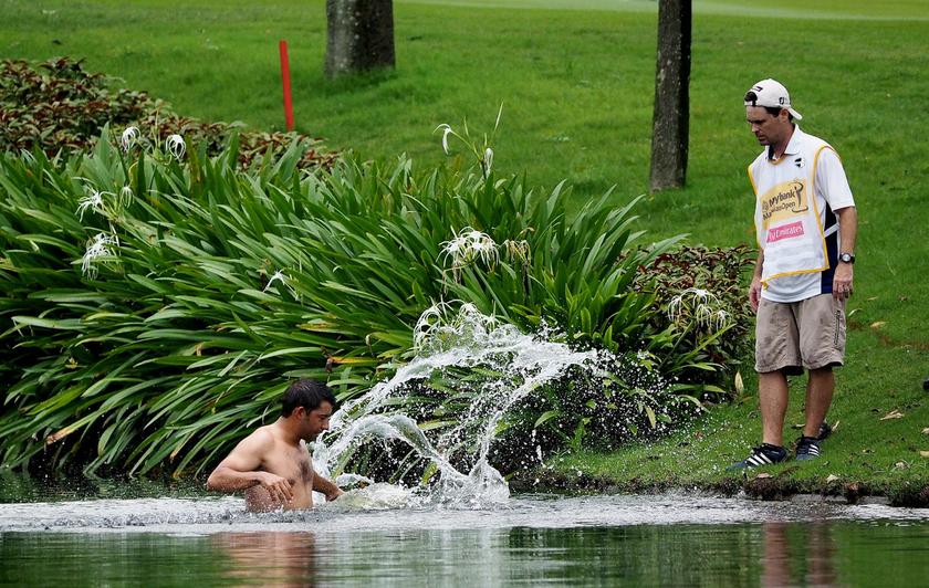 Spanish golfer Pablo Larrazabal (left) jumps into a water hazard to escape a swarm of attacking hornets during the Malaysian Open today, on April 18, 2014. u00e2u20acu201d Bernama pic