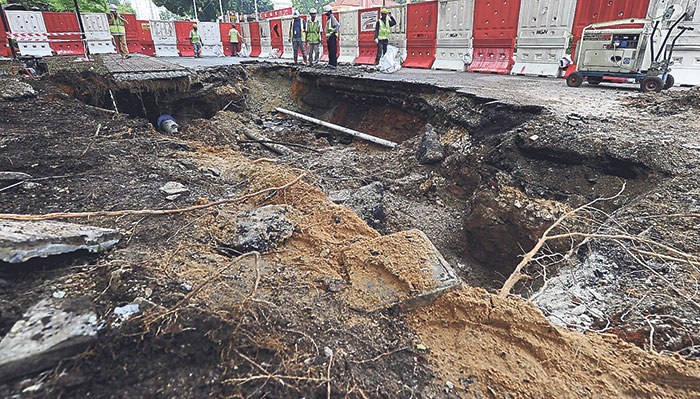 MRT construction workers look at the sinkhole in front of Menara Worldwide on Saturday. u00e2u20acu201d file picture