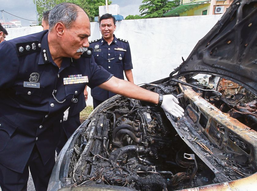 Abdul Rahman inspects the burnt car at the district police headquarters in Bertam, May 27, 2014. u00e2u20acu201d file picture