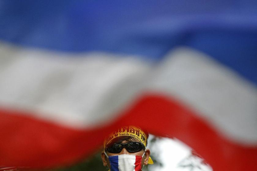 A masked anti-government protester behind the national flag at a rally outside parliament where members of the Senate gathered for a meeting, in Bangkok May 16, 2014 Reuters