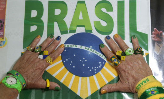 Brazilian football fan Marilza Guimaraes da Silva, 63, holds up her hands decorated with accessories in Brazil's national colours at her home in Brasilia May 27, 2014. u00e2u20acu201d Reuters pic