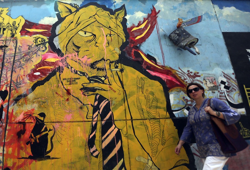 A woman walks past a graffiti in Cairo May 21, 2014. u00e2u20acu201du00c2u00a0Reuters pic