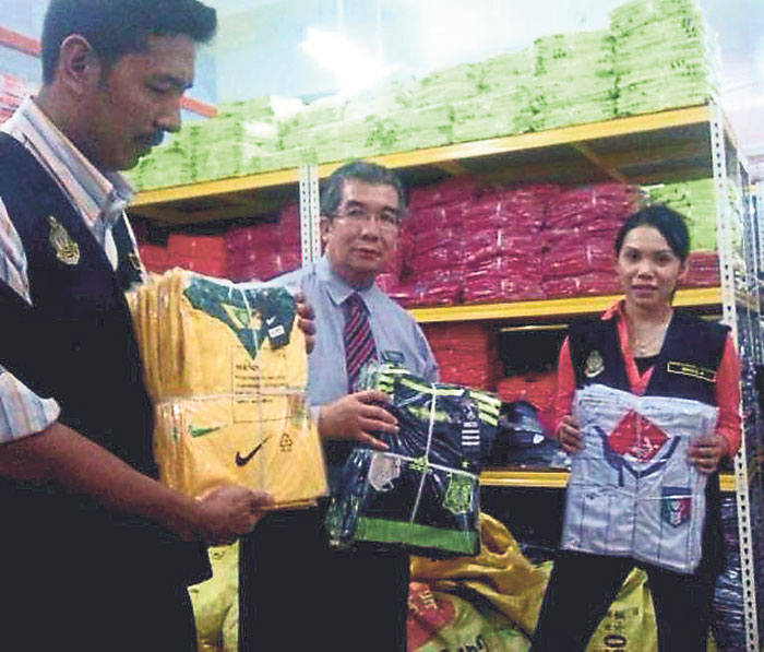 Rosli (left), Aswadi and another officer show the fake World Cup jerseys. u00e2u20acu201d Malay Mail pic