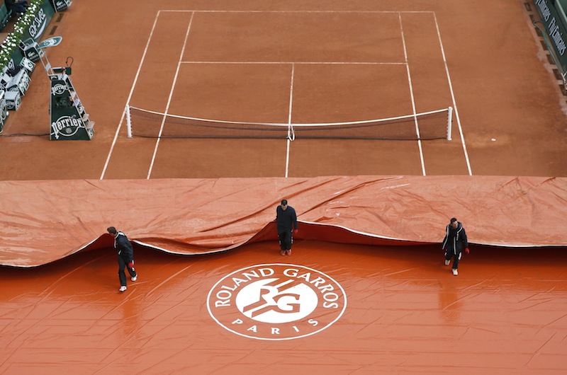 Workers remove a tarp from Court Suzanne Lenglen at the French Open tennis tournament at the Roland Garros stadium in Paris May 26, 2014. u00e2u20acu201d Reuters pic