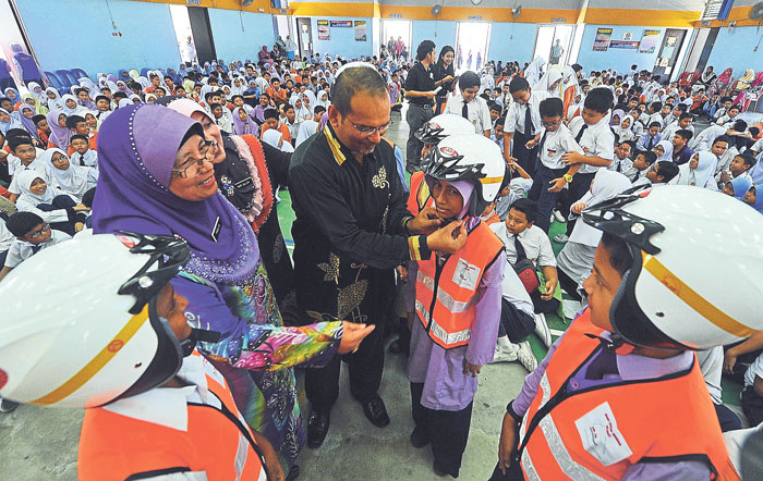 Mohd Rusdi demonstrates the proper use of a safety helmet and reflective vest. u00e2u20acu201d Picture by Zuraneeza Zulkifli