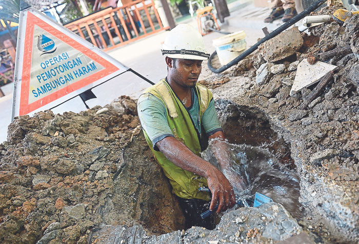 A Syabas contractor disconnects the pipe that has been illegally installed for over two years. u00e2u20acu201d Picture by Razak Ghazali