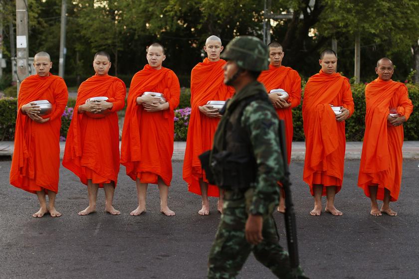 A soldier walks past barefoot Buddhist monks begging for alms outside a temple near Government House in Bangkok May 23, 2014. u00e2u20acu201d Reuters pic