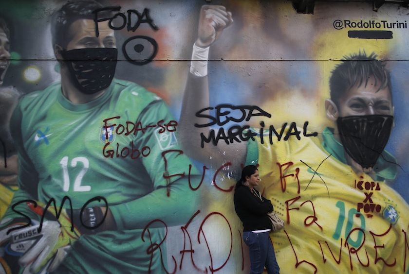 A woman stands in front of a graffiti by Brazilian artist Rodolfo Turini of Brazilian players Neymar and goalkeeper Julio Cesar covered with a mask, in Sao Paulo May 28, 2014. u00e2u20acu201d Reuters pic