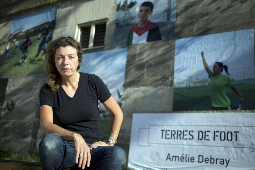 French photographer Amelie Debray poses in front pictures she took, part of the exhibition u00e2u20acu02dcTerres de footu00e2u20acu2122 (Lands of football), on June 19, 2014 in Paris. The exhibition will run until July 14, 2014 on the Seine's river bank. u00e2u20acu201d AFP pic