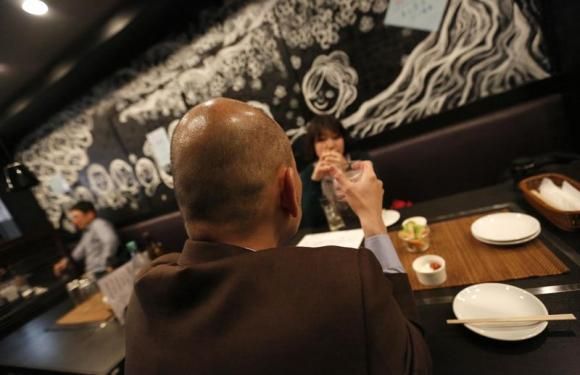 Salaryman Shiro Fukai (front), 48, drinks distilled spirit at the Otasuke 'izakaya' style pub and restaurant in Tokyo May 8, 2014 Reuters
