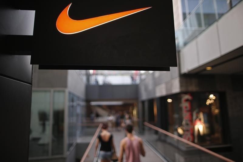 People walk past a Nike shop under the company logo at the Sanlitun shopping area in central Beijing, August 8, 2013 Reuters