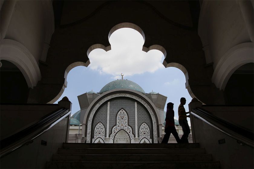 A couple walk past the Wilayah Persekutuan Mosque before performing Zuhur prayers. u00e2u20acu201d Picture by Yusof Mat Isa