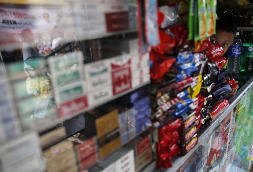 A child looks out from behind the counter of a kiosk selling cigarettes and snacks in Jakarta June 24, 2014. u00e2u20acu201d Reuters pic  