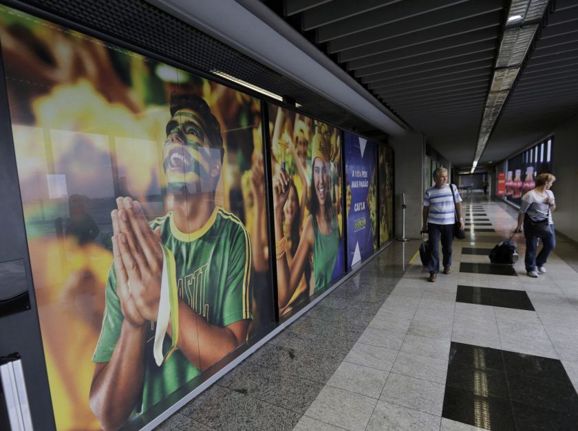 People arrive past a large banner with images of Brazil fans at the international airport in Curitiba, June 8, 2014.  u00e2u20acu201d Reuters pic