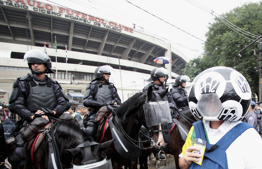 A football fan wearing a ball-shaped hat walks past riot police before an international friendly match between Brazil and Serbia at Morumbi in Sao Paulo June 6, 2014. u00e2u20acu201d Reuters pic