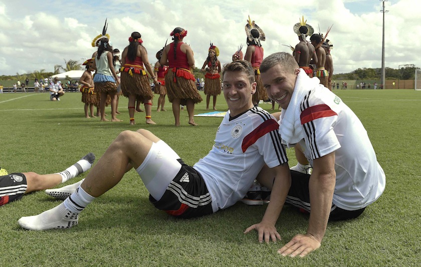 Germany's national players Mesut Oezil (left) and Lukas Podolski sit in front of a group of native Brazilians after a training session of the German team in the village Santo Andre near Porto Seguro June 9, 2014. u00e2u20acu201d Reuters pic