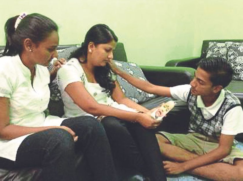 Tevi Darsiny (left) and Karan Dinish comfort their mother Indira Gandhi, who holds a photograph of Prasana. — The Malay Mail pic