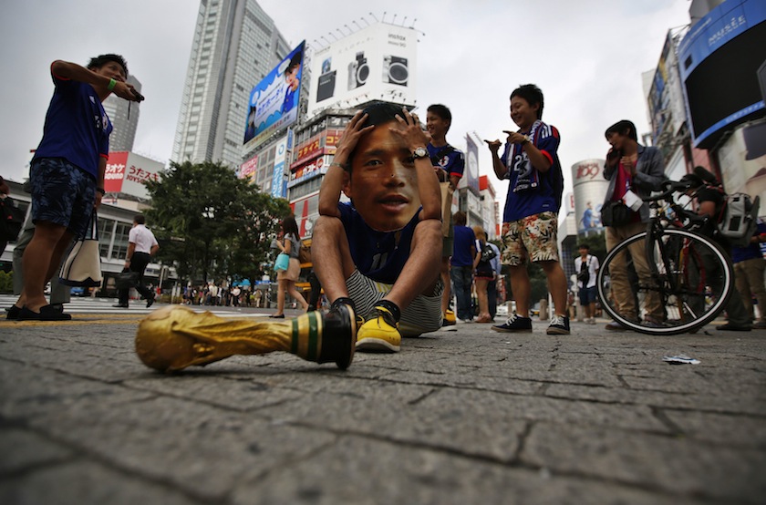A fan wearing mask of Japan's national soccer player Yuto Nagatomo reacts next to a mock World Cup trophy after Japan was defeated in their World Cup match against Colombia, at Shibuya shopping and amusement district in Tokyo June 25, 2014.u00c2u00a0u00e2u20acu201d Reuters p