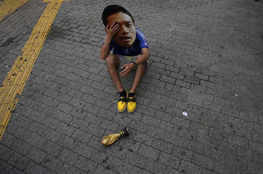 A football fan wearing mask of Japanu00e2u20acu2122s national player Yuto Nagatomo reacts next to a mock World Cup trophy after Japan was defeated in their World Cup match against Colombia in Tokyo June 25, 2014. u00e2u20acu201d Reuters pic