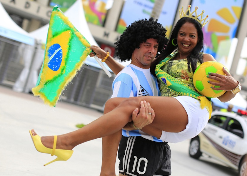 A street busker, dressed as Diego Maradona, carries another busker with the Brazilian flag as they wait for tourists to take pictures with them outside Maracana stadium in Rio de Janeiro, ahead of the 2014 World Cup June 6, 2014. u00e2u20acu201du00c2u00a0Reuters pic