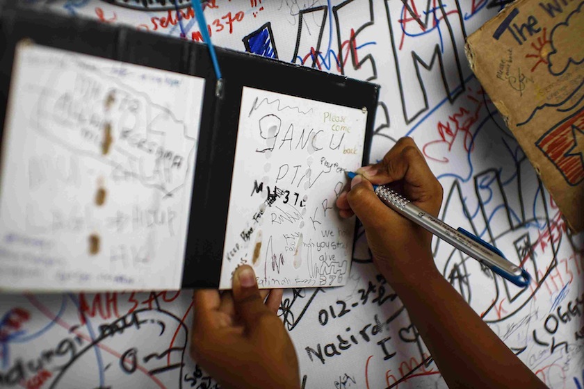 A child writes messages of hope for passengers of missing Malaysia Airlines Flight MH370 at Kuala Lumpur International Airport (KLIA) outside Kuala Lumpur June 14, 2014. u00e2u20acu201du00c2u00a0Reuters pic