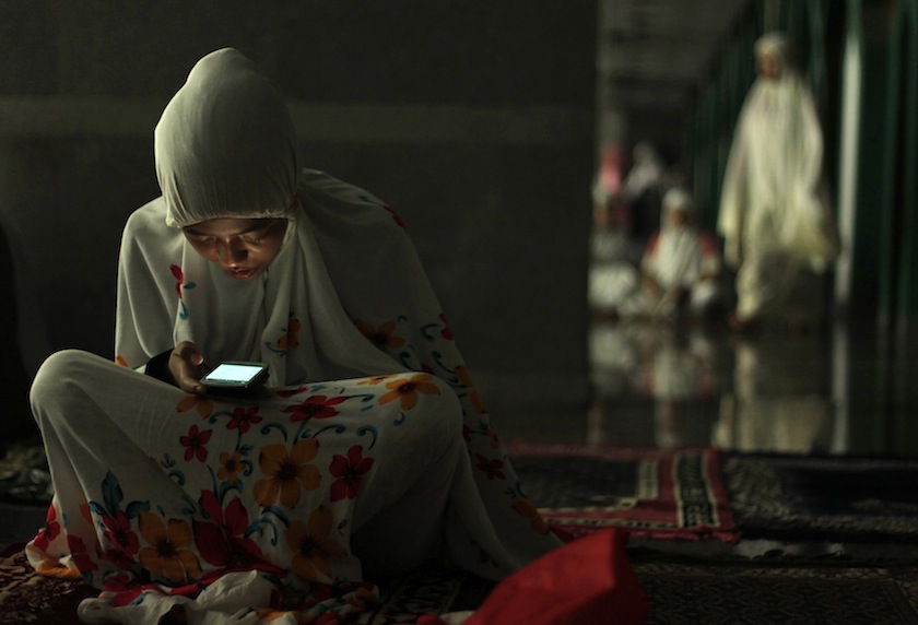 A Muslim woman uses her phone before the start of an evening mass prayer session'tarawih' to mark the holy fasting month of Ramadan at Al Markaz Al Islami Mosque in Makassar, South Sulawesi Province June 28, 2014.u00c2u00a0u00e2u20acu201du00c2u00a0Reuters pic