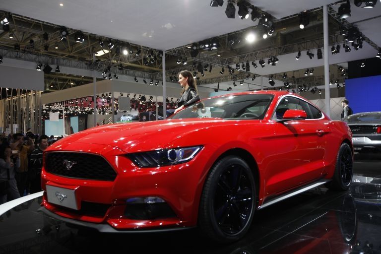 A model poses by a red Mustang 50th anniversary edition car on display at the China International Exhibition Centre in Beijing. ― AFP pic