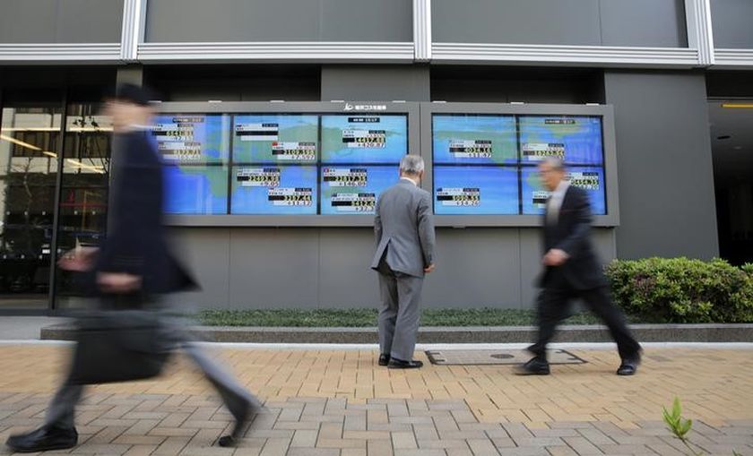 A man looks at an electronic board displaying Japan's Nikkei average (top centre) and various countries' stock indices, as passers-by walk past outside a brokerage in Tokyo April 16, 2014. u00e2u20acu201d Reuters pic