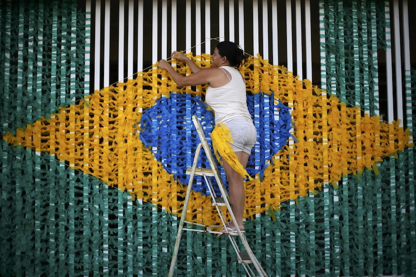 A woman ties ribbons in the form of the national flag of Brazil on a street decorated with references to the 2014 World Cup, in the neighbourhood of Ceilandia in Brasilia, June 11, 2014.u00c2u00a0u00e2u20acu201du00c2u00a0Reuters pic